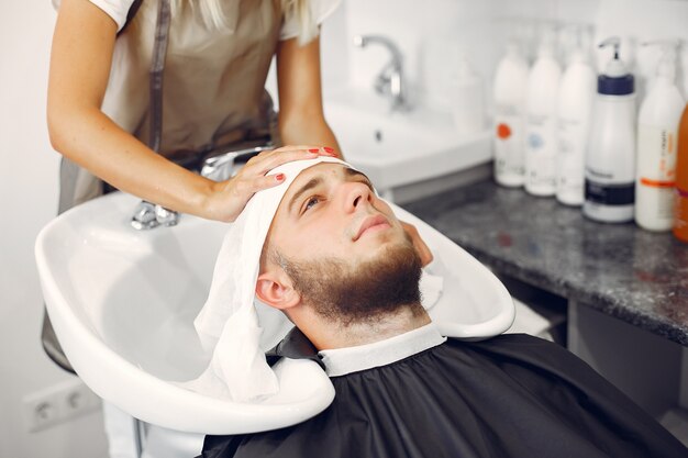 Woma washing man's head in a barbershop