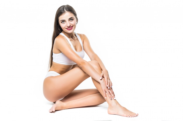 Woman in active wear sitting on floor isolated on white wall