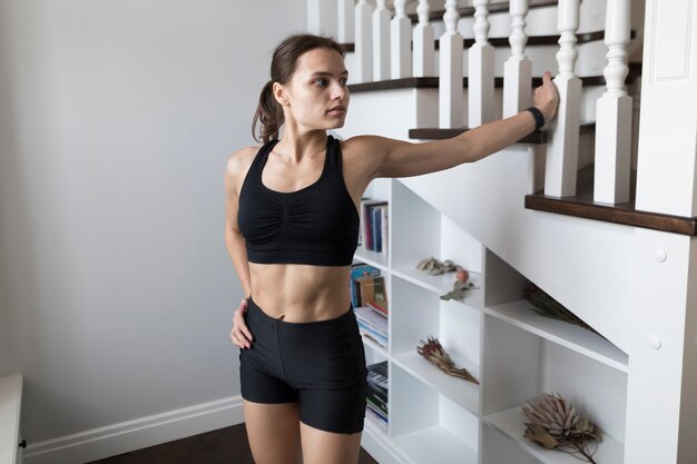 Woman in activewear posing next to stairs