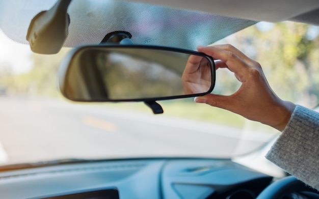 A woman adjusting a rear view mirror while driving car