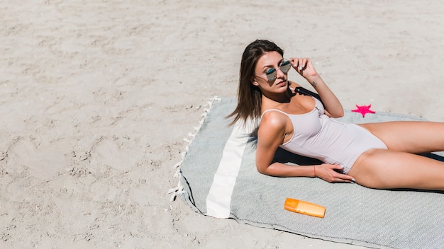 Foto gratuita donna che regola gli occhiali da sole sulla spiaggia