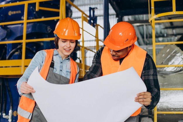 Woman and african american worker standing with a plan in a factory