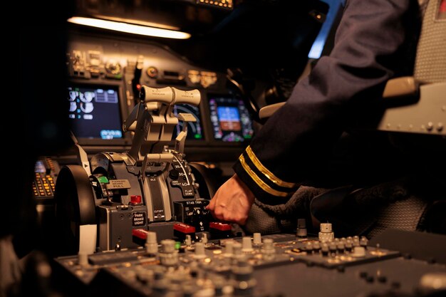 Женщина-авиалайнер нажимает кнопки приборной панели в кабине самолета, готовясь к взлету с помощью рычага двигателя или ручки. Второй пилот использует команды панели управления и навигационный радар на лобовом стекле. Закрыть.