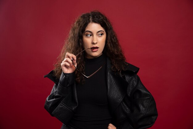 woman in all black outfit holding glasses and posing.