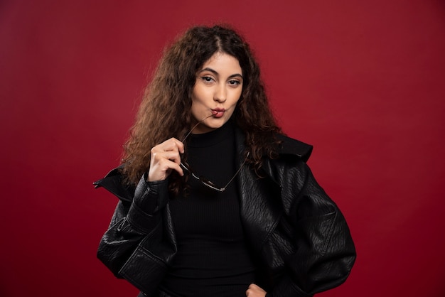 woman in all black outfit holding glasses and posing.