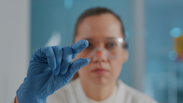 Free photo woman analyzing blood sample on lab glassware tray in science laboratory. biology engineer with gloves looking at dna substance for molecule test and diagnosis research. close up