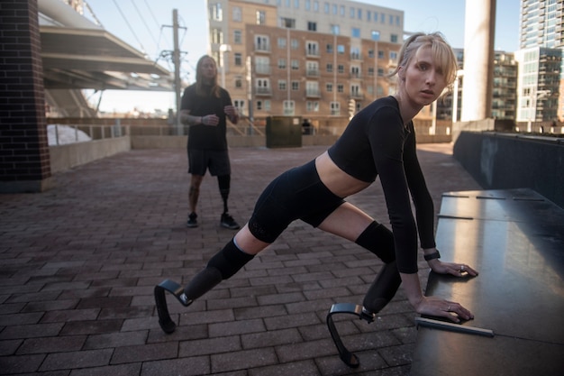 Бесплатное фото Женщина и мужчина с инвалидностью ног тренируются в городе