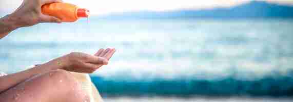 Free photo a woman applies sunscreen on the beach copy space