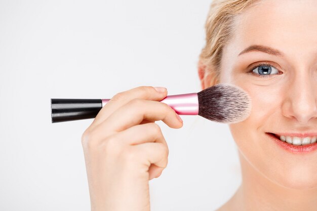 woman apply makeup on face with brush