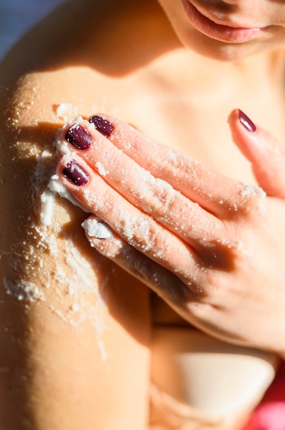 Woman applying body scrub on her shoulder