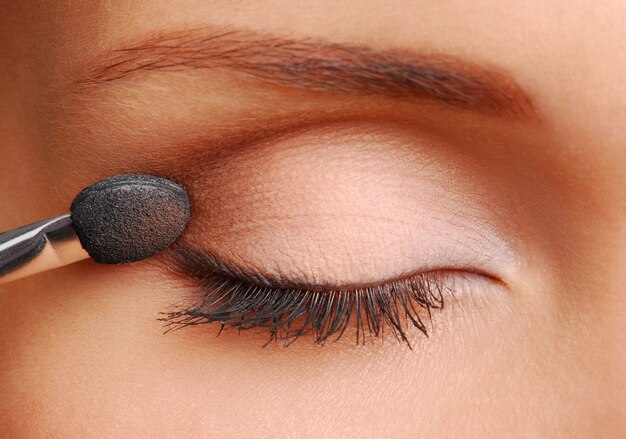 Woman applying cosmetic with applicator on the lid