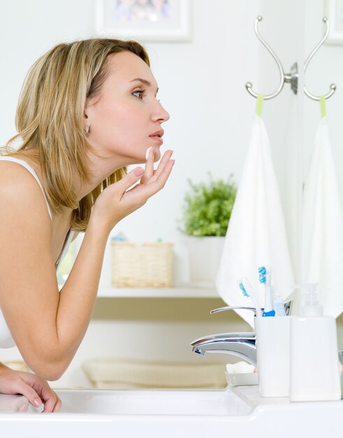 Woman applying  cream on cheek - indoors