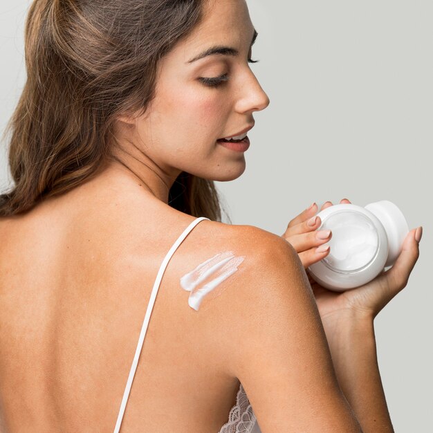 Woman applying cream on her back