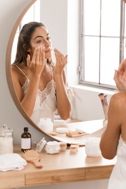 Woman applying cream in the mirror