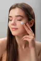 Free photo woman applying face cream side view