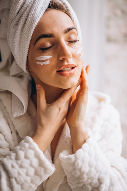 Foto gratuita donna che applica crema per il viso