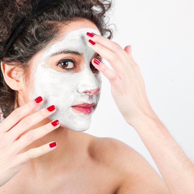 Woman applying face mask on her face against white background