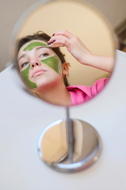 Женщина, применяя маску в зеркало
