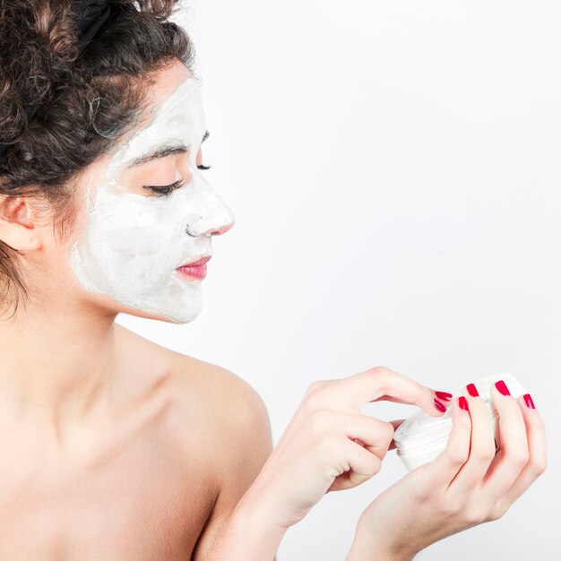 Woman applying facial mask on her face against white background