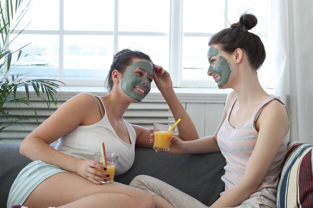 Woman applying a facial mask to her friend, skin care concept