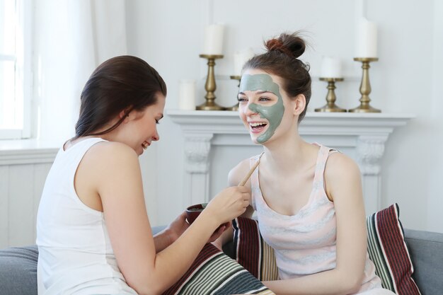 Woman applying a facial mask to her friend