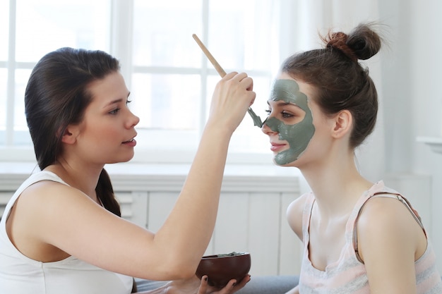Woman applying a facial mask to her friend