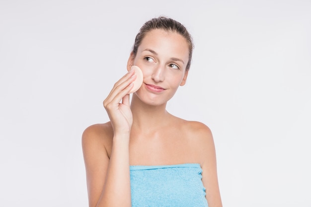 Woman applying facial sponge 