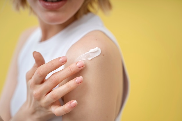 Woman applying lotion on shoulder