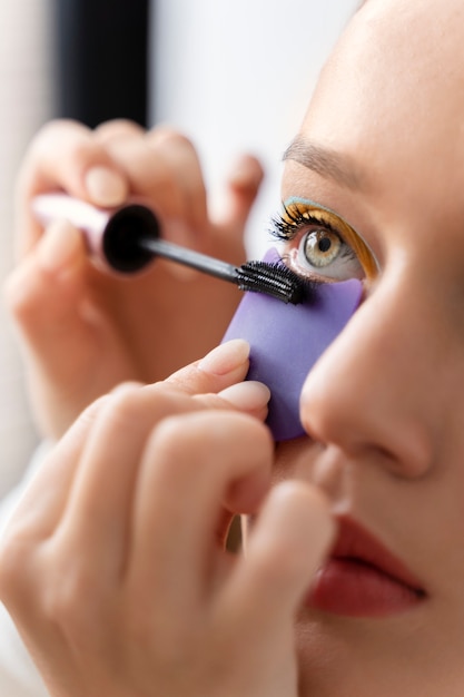 Woman applying mascara close up