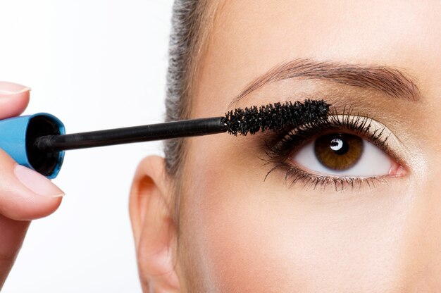 Woman applying mascara on her eyelashes - macro shot