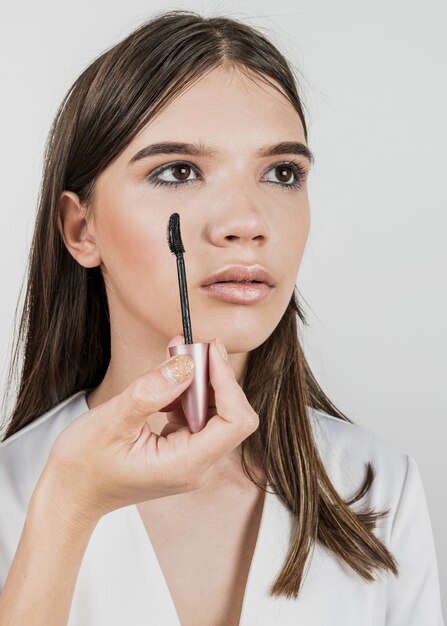 Woman applying mascara on young model