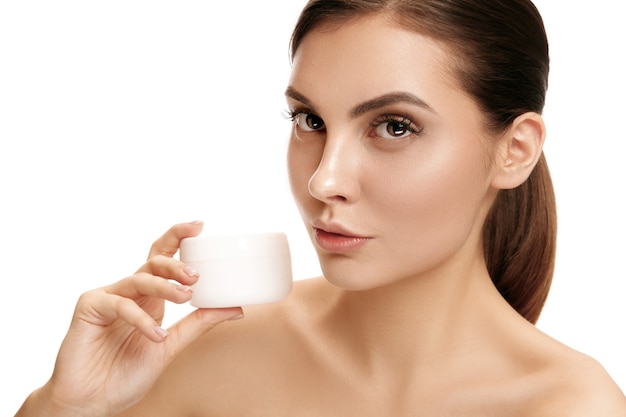 Woman applying moisturizer cream on face at studio