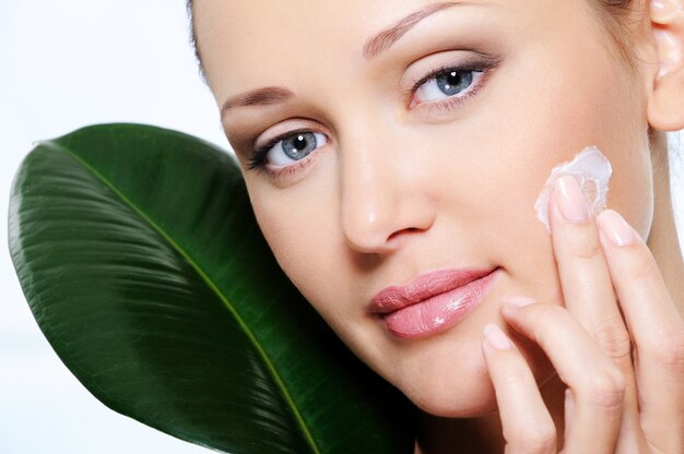 Woman applying moisturizer  cream on her  fresh beauty face