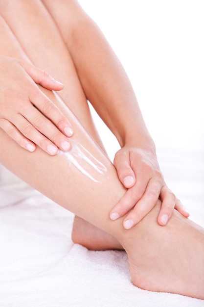 Woman applying moisturizer cream on the legs