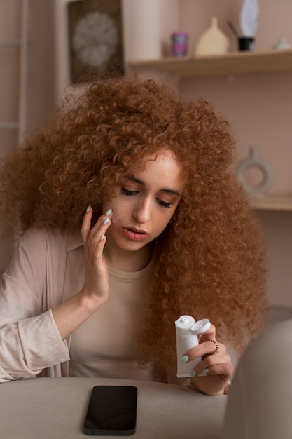 Foto gratuita donna che applica una crema idratante durante la sua routine di bellezza