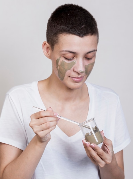 Woman applying mud treatment on face