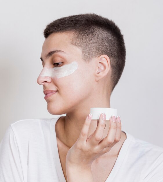 Woman applying skin care cream on face