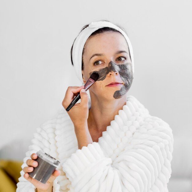Woman applying spa organic facial mask with brush