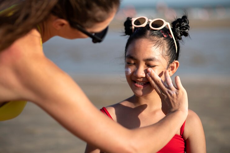 Free Photo woman applying sunscreen on kid front view