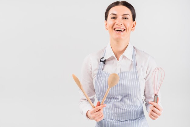 Woman in apron smiling and holding utensil