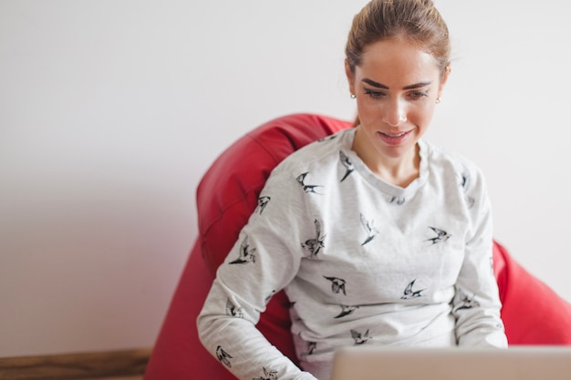 Woman on armchair looking at laptop