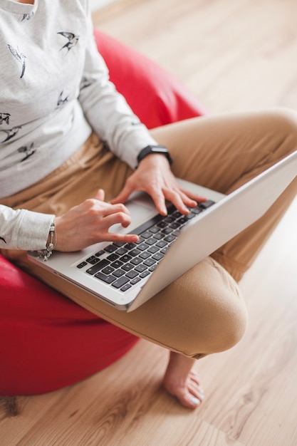 Woman on armchair typing on laptop