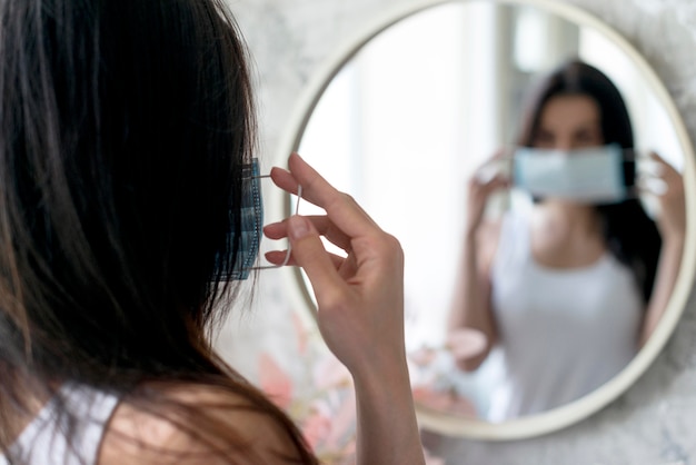 Woman arranging medical mask at home