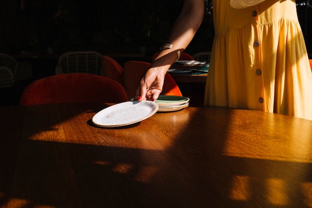 Foto gratuita donna che organizza i piatti sul tavolo di legno