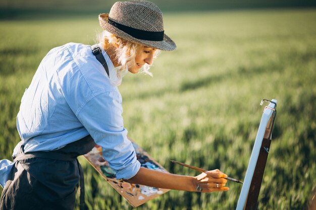 Woman artist painting with oil paints in a field