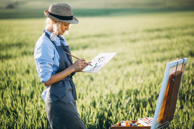 Woman artist painting with oil paints in a field