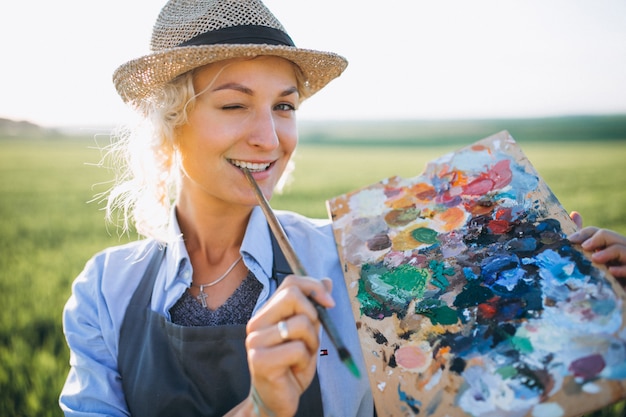 Woman artist painting with oil paints in a field