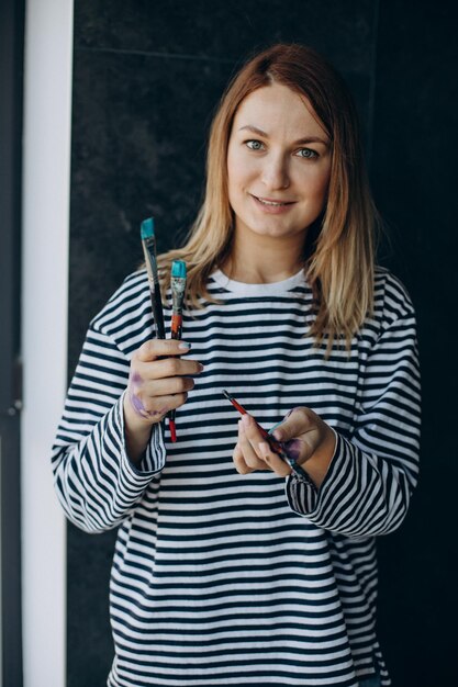 Woman artist with with painted hands holding brushes