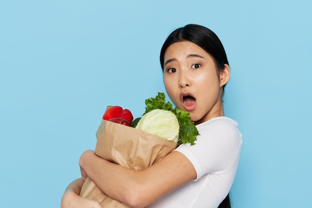 Женщина азиатская внешность пищевой пакет здоровая еда синий фон