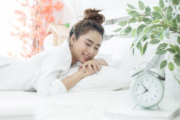 woman asleep in bed while her alarm shows the early time at home in bedroom